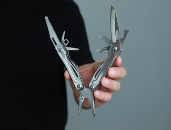 Man holding multitool on grey background, closeup