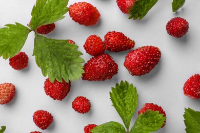 Photo of Many fresh wild strawberries and leaves on white background, flat lay