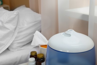 Photo of Air humidifier, tissues and medicine near bed in room, closeup. Flu season
