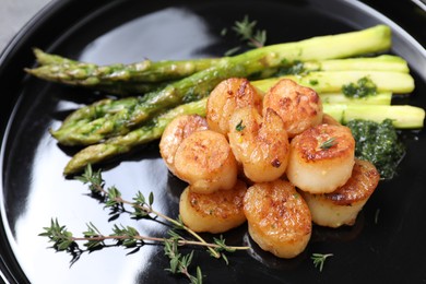 Delicious fried scallops with asparagus and thyme on plate, closeup