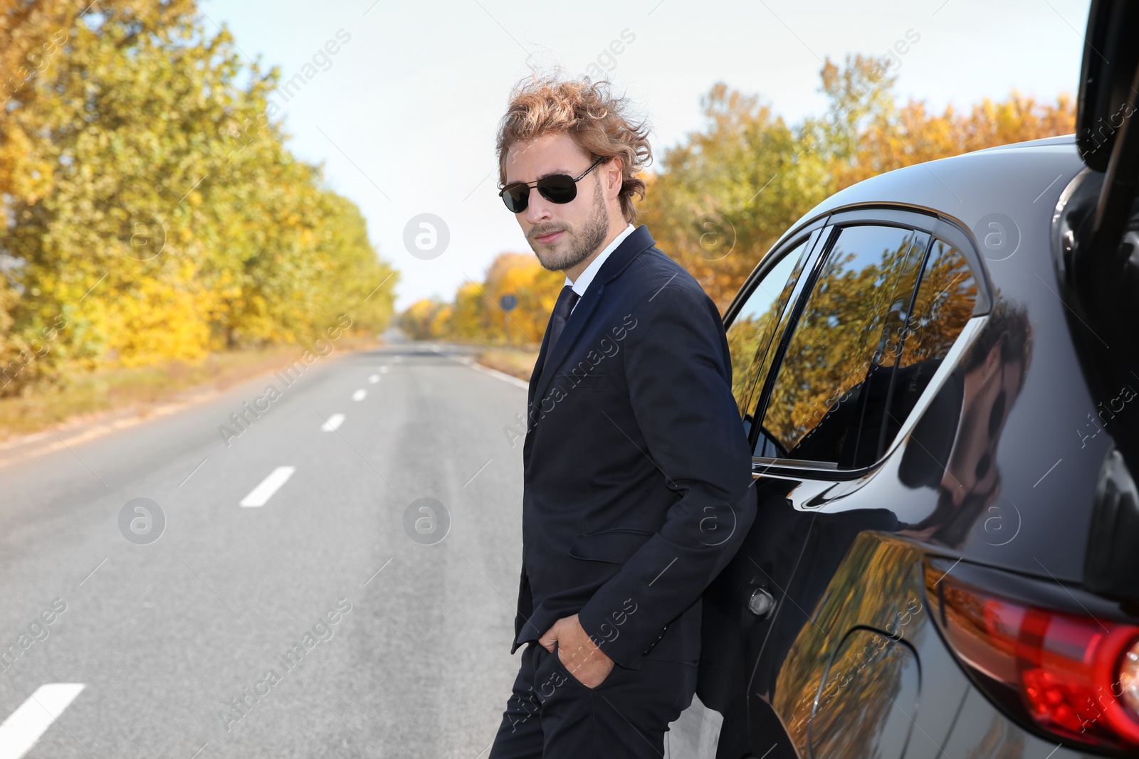 Photo of Young businessman near modern car on sunny day, outdoors