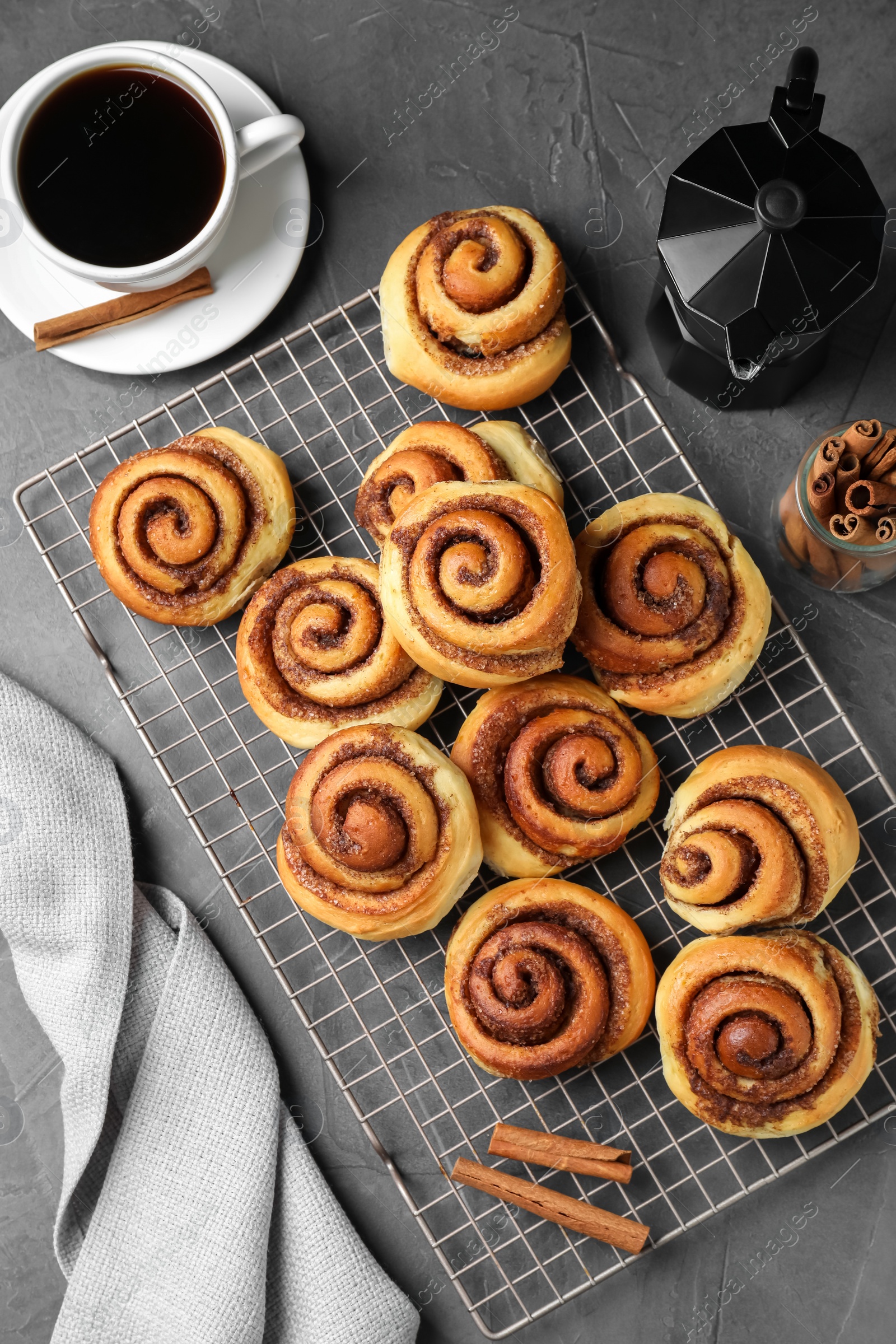 Photo of Tasty cinnamon rolls served on black table, flat lay