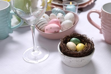 Photo of Festive table setting with painted eggs, closeup. Easter celebration