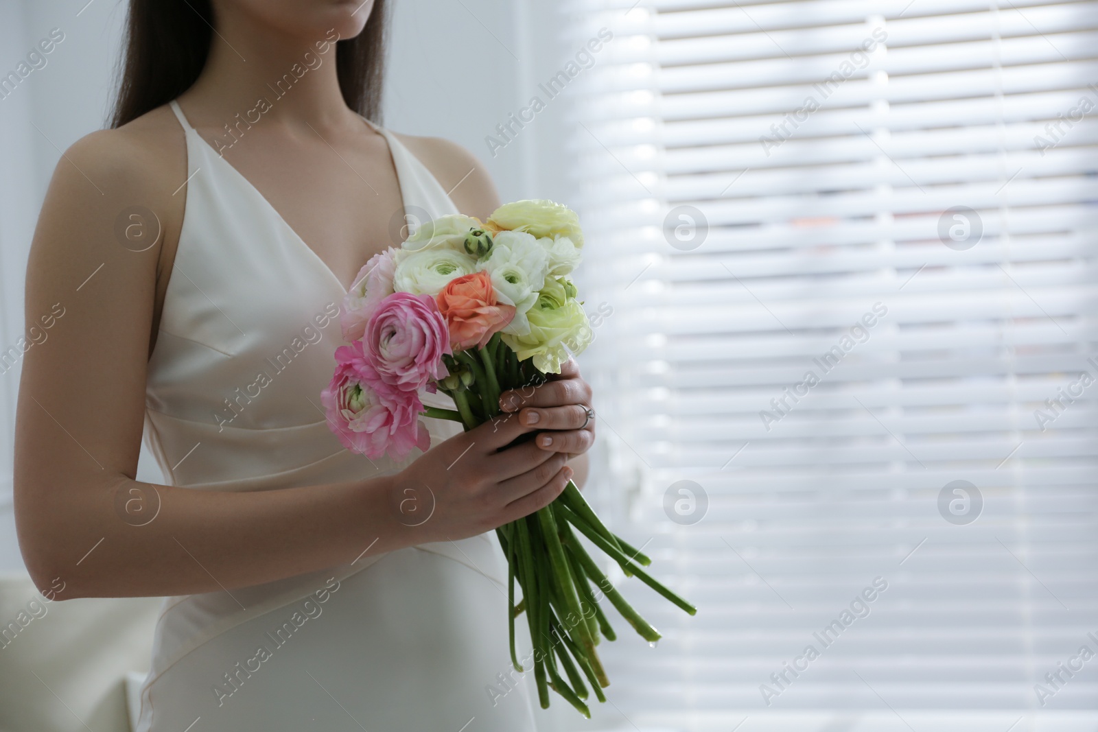 Photo of Bride with beautiful ranunculus bouquet indoors, closeup. Space for text