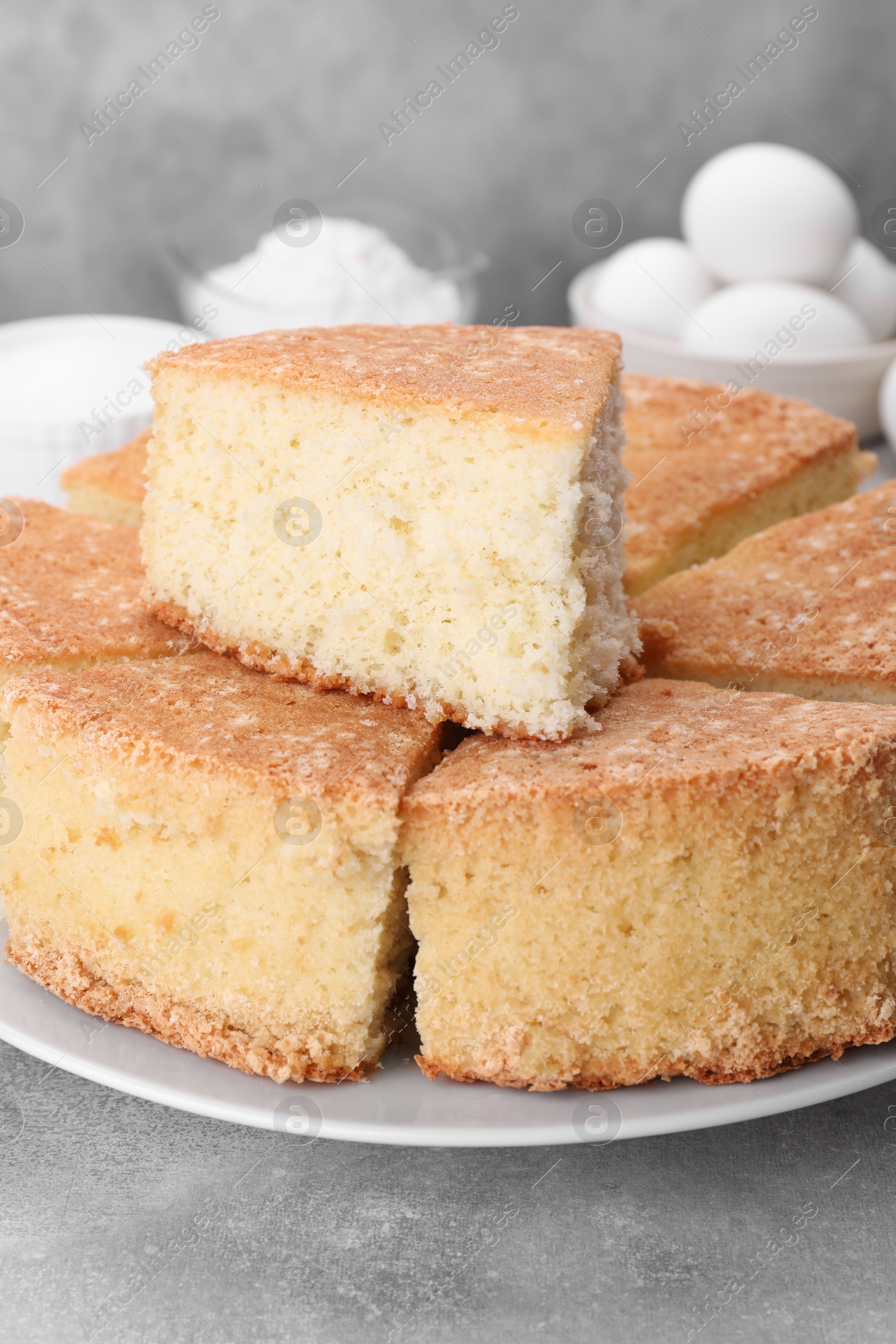 Photo of Pieces of tasty sponge cake on light grey table, closeup