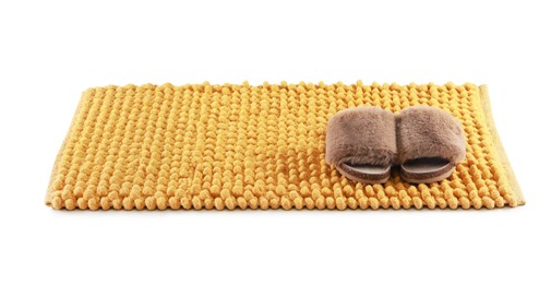 Photo of New yellow bath mat with fluffy slippers isolated on white