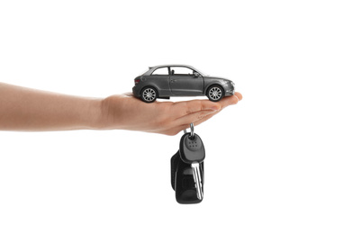 Woman holding key and miniature automobile model on white background, closeup. Car buying