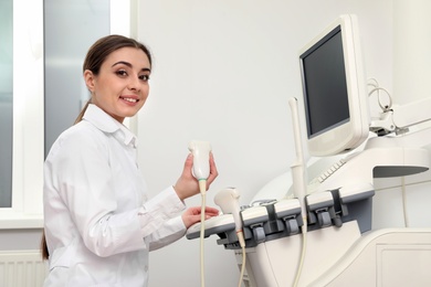 Professional sonographer using modern ultrasound machine in clinic