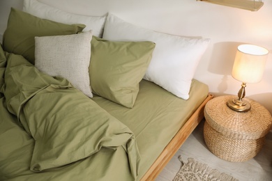 Photo of Comfortable bed with olive green linen in modern room interior