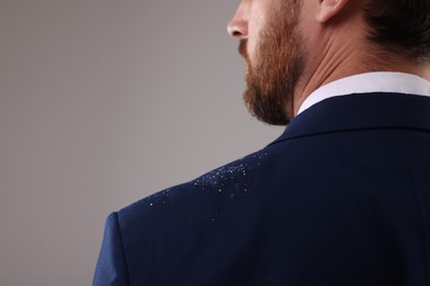 Photo of Man with dandruff on his suit against grey background, closeup. Space for text