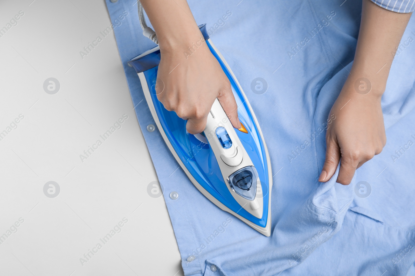 Photo of Woman ironing clean shirt on white table, top view