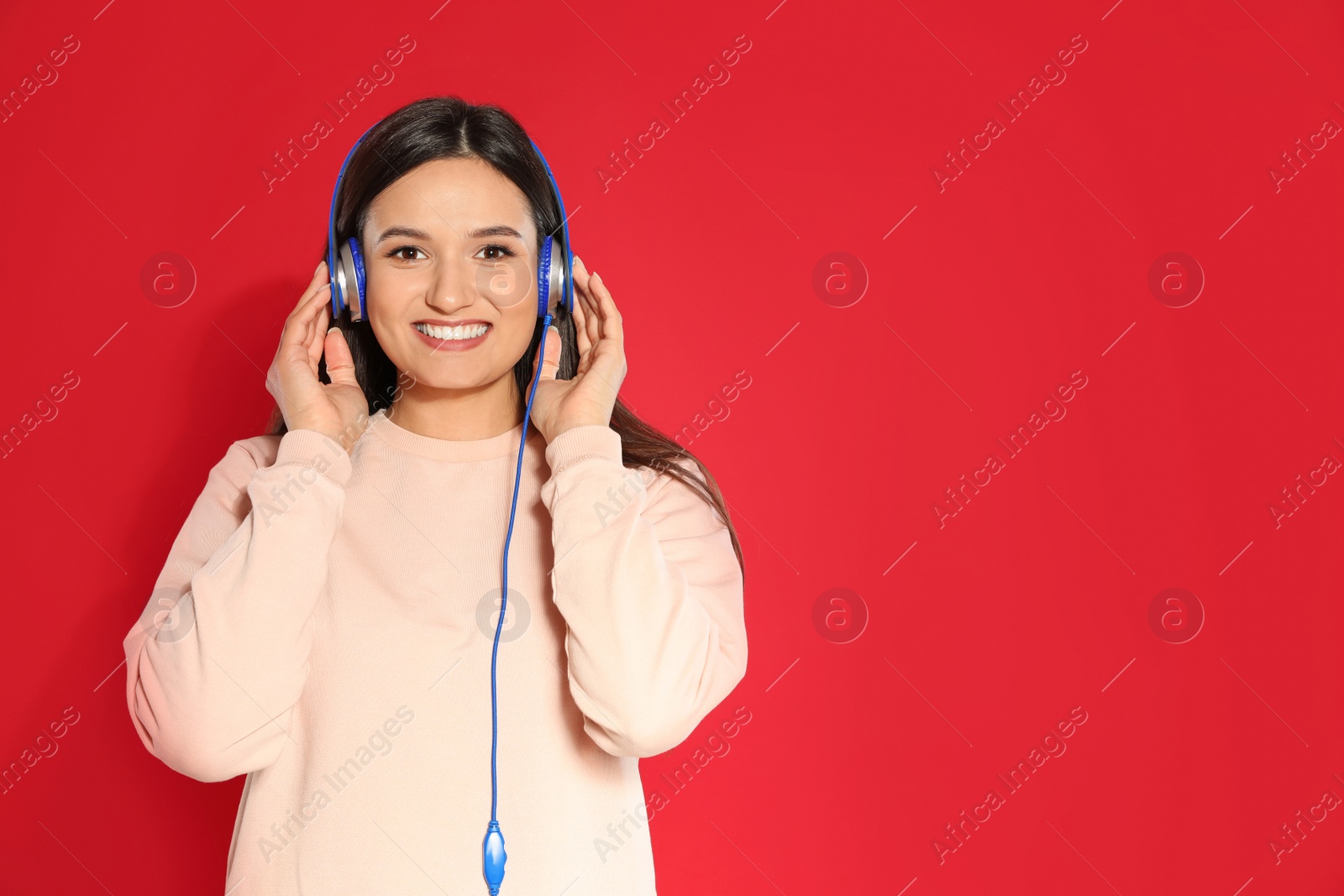 Photo of Attractive young woman enjoying music in headphones on color background. Space for text