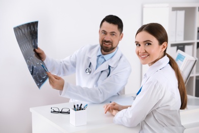Photo of Orthopedists examining X-ray picture at desk in clinic