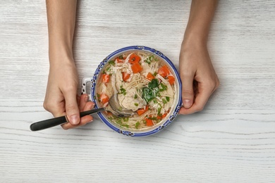 Photo of Woman eating fresh homemade chicken soup at table, top view