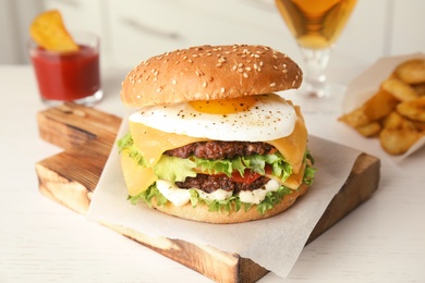 Photo of Tasty burger with fried egg on wooden board