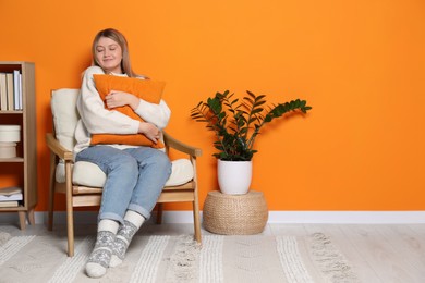 Photo of Young woman relaxing in armchair at home, space for text. Interior design