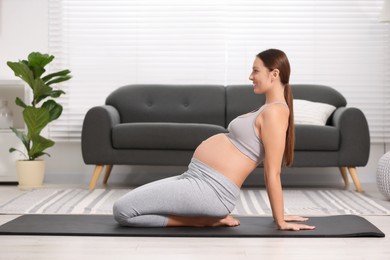 Photo of Pregnant woman doing exercises on yoga mat at home