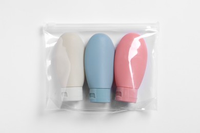 Photo of Cosmetic travel kit in plastic bag on white background, top view