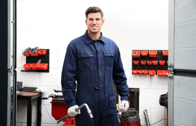 Professional worker with wheel wrench in shop of modern tire service