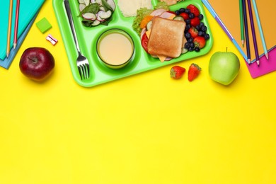 Photo of Flat lay composition with serving tray, tasty healthy food and school stationery on yellow background. Space for text