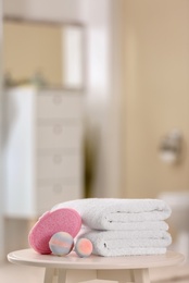 Photo of Clean towels and toiletries on table against blurred background