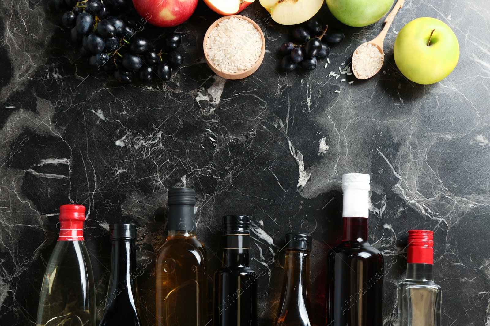 Photo of Flat lay composition with different kinds of vinegar and ingredients on marble background. Space for text