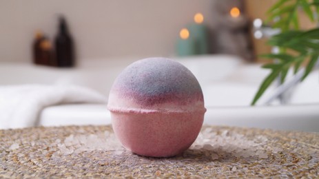 Photo of Beautiful bath bomb on wicker mat in bathroom