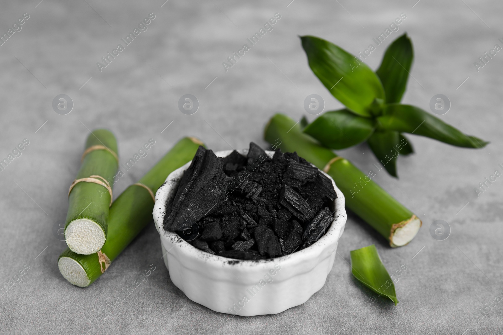 Photo of Fresh bamboo and charcoal on light gray table, closeup