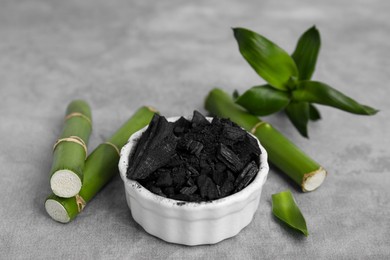 Photo of Fresh bamboo and charcoal on light gray table, closeup