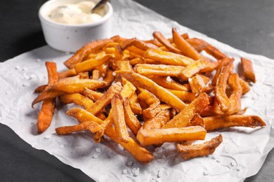 Photo of Delicious sweet potato fries and sauce on black table, closeup