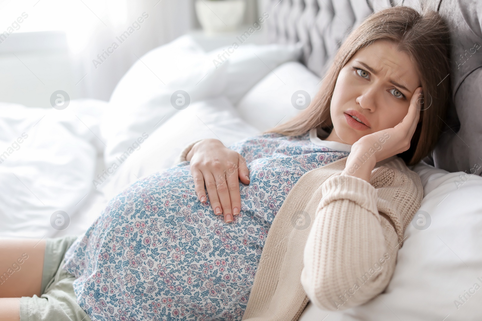 Photo of Young pregnant woman suffering from headache at home