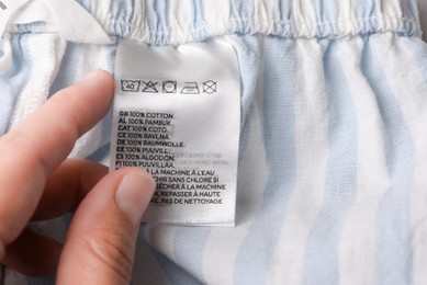 Photo of Woman holding clothing label on striped garment, closeup