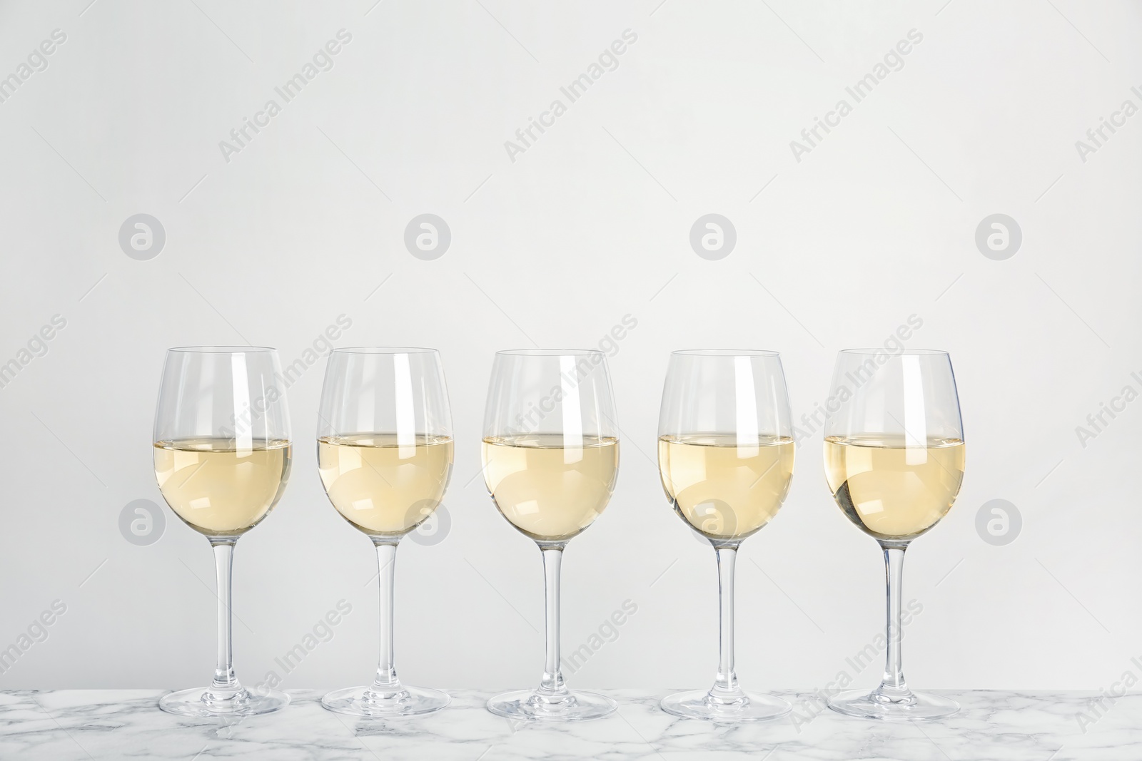 Photo of Glasses with white wine on light background