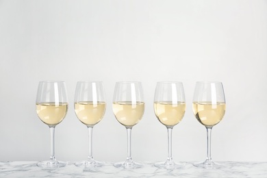 Glasses with white wine on light background