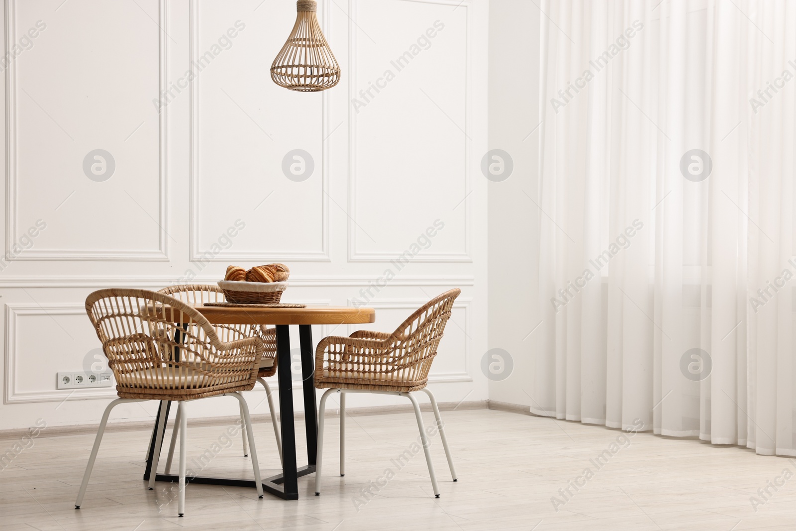 Photo of Dining room interior with wooden table and wicker chairs. Space for text