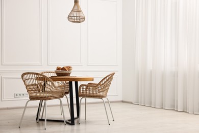 Dining room interior with wooden table and wicker chairs. Space for text