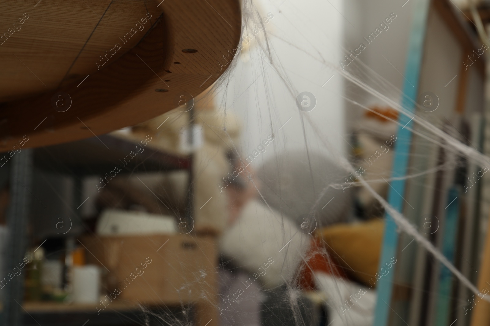 Photo of Old cobweb on wooden table indoors, closeup