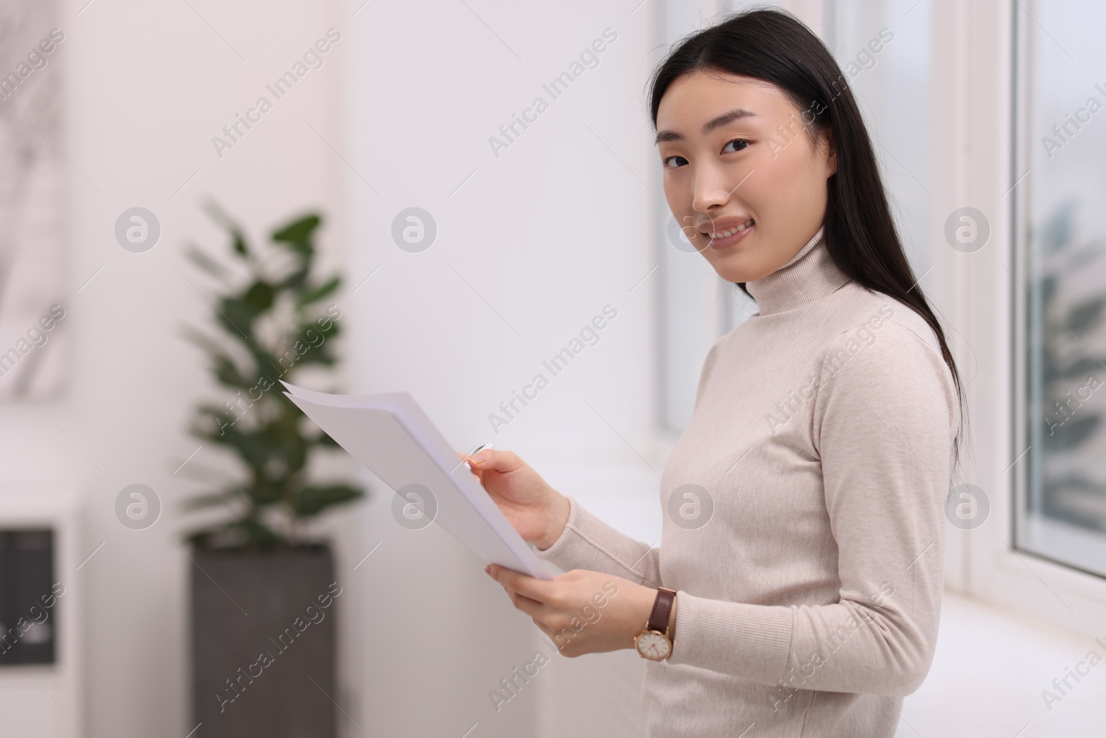 Photo of Portrait of smiling businesswoman with documents in office