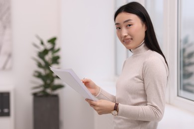 Photo of Portrait of smiling businesswoman with documents in office