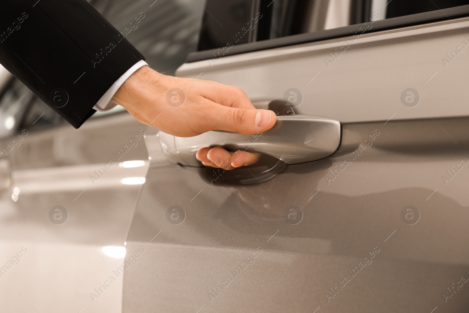 Photo of Young salesman in suit opening car door, closeup view