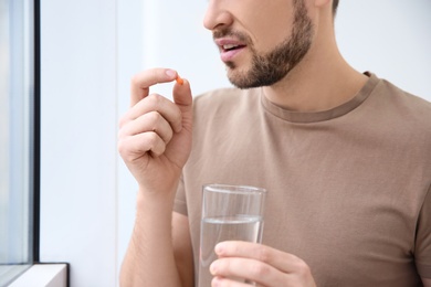 Young man taking pill indoors