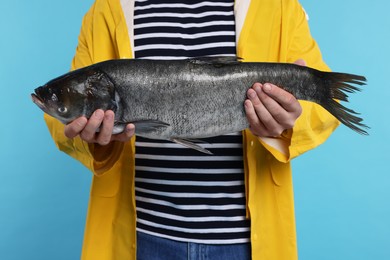 Photo of Fisherman with caught fish on light blue background, closeup