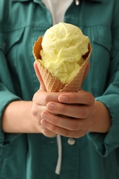 Photo of Woman holding yellow ice cream in wafer cone, closeup