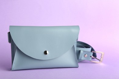 Stylish light blue women's bag on violet background