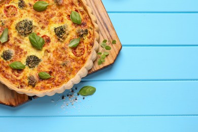 Photo of Delicious homemade vegetable quiche on light blue wooden table, top view. Space for text