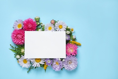 Photo of Flat lay composition with beautiful aster flowers and blank card on light blue background. Space for text