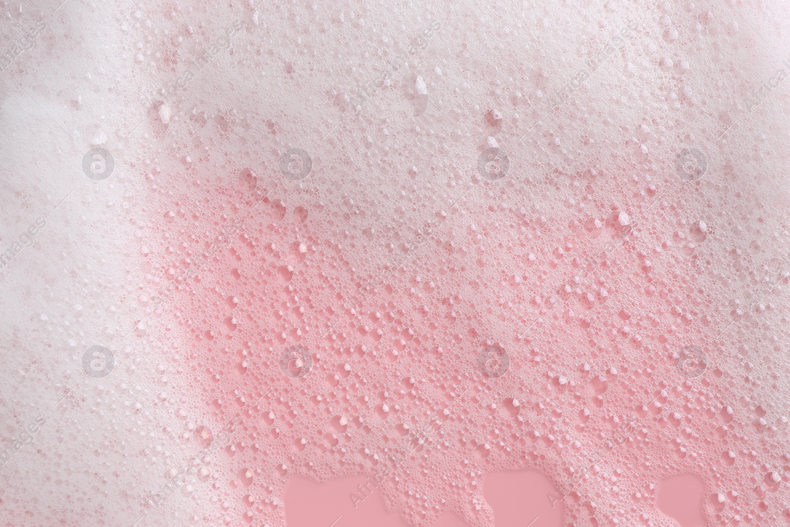 Photo of White fluffy foam on pink background, top view