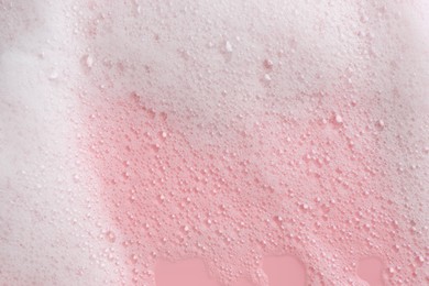 Photo of White fluffy foam on pink background, top view