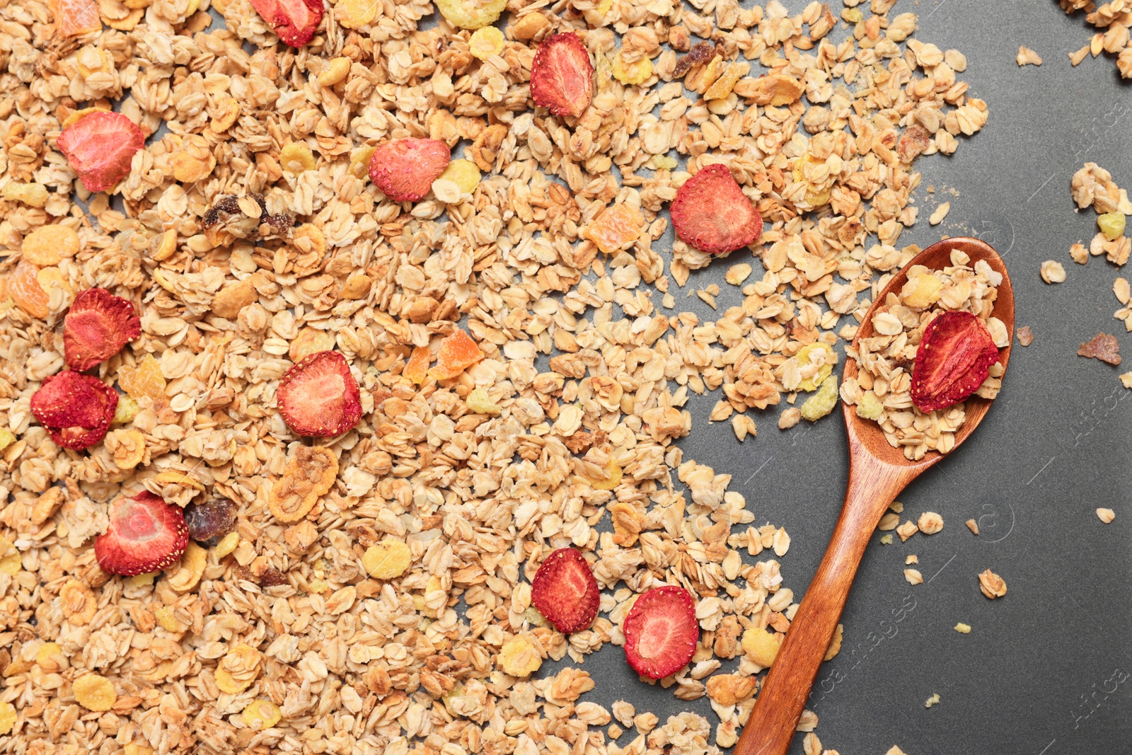 Photo of Making granola. Mixture of oat flakes, other ingredients and spoon on baking tray, flat lay