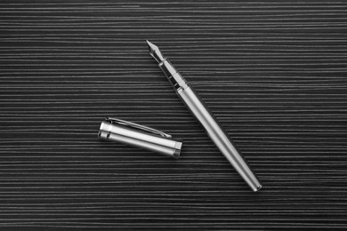 Photo of Stylish silver fountain pen on black wooden table, top view